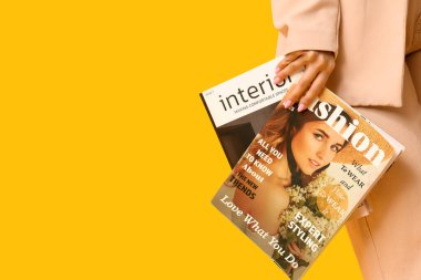 Sarı arka planda dergileri olan güzel bir genç kadın, yakın plan.