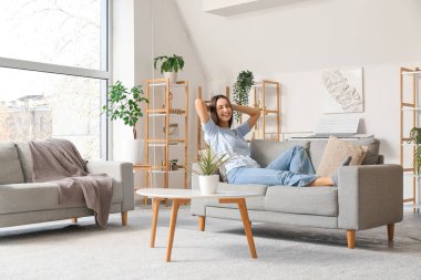 Oturma odasındaki rahat koltukta dinlenen genç ve güzel bir kadın.