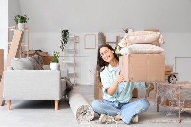 Taşındığı gün oturma odasında karton kutuları olan genç bir kadın.