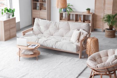 Oturma odasının içinde yumuşak kanepe, bitki ve dizüstü bilgisayar var.