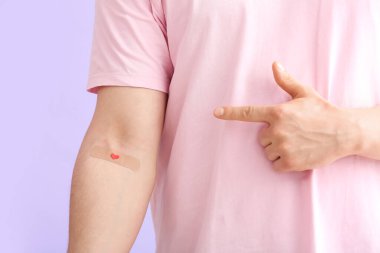 Kan donörü, eflatun arka planda uygulamalı tıbbi yamaya işaret ediyor. Yakın plan.