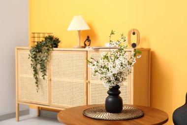 Modern oturma odasının iç tarafındaki masanın üzerinde çiçek açan bir vazo.