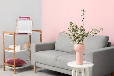 Çiçek açan güzel dalları olan bir vazo ve evdeki kanepe.