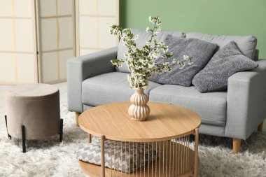 Masadaki vazoda güzel dallar, katlanan ekran ve oturma odasındaki rahat kanepe.