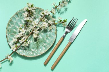 Turkuaz arka planda çiçek açan dalları olan güzel masa ayarları