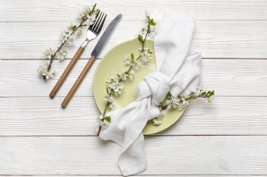 Beyaz ahşap arka planda çiçek açan dalları olan güzel bir masa.