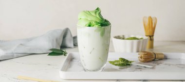 Hafif arka planda bir bardak lezzetli dalgona matcha latte.