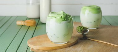 Bir bardak lezzetli dalgona matcha latte ahşap masada.