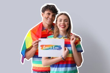 Gökkuşağı renkli LGBT bayrağı taşıyan genç bir çift açık arkaplanda aşk yazılı kağıt taşıyor
