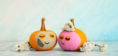 Yüzleri çizilmiş şirin balkabakları, açık mavi arka planda kozmetik maskeler ve çiçekler. Spa konsepti