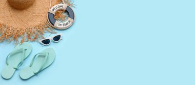 Güneş gözlüğü, yüzük şamandırası, parmak arası terlik ve açık mavi arka planda açık mavi şapka.