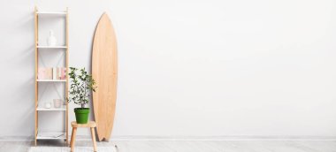 Sörf tahtası, raf ünitesi ve ev bitkisi olan bir ışık odası. Tasarım için pankart