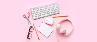 Modern bilgisayar klavyesi, bilgisayar faresi, kulaklık, gözlük ve pembe arka plan kırtasiyesi