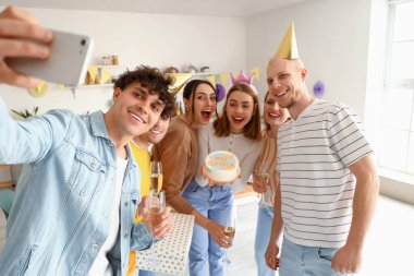 Doğum günü pastası olan bir grup genç arkadaş mutfakta selfie çekiyor.