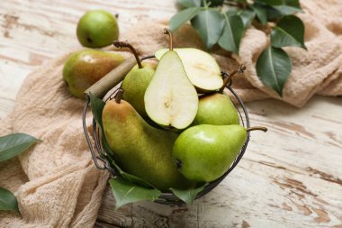 Tahta masada olgun armutlarla dolu sepet, yakın plan.