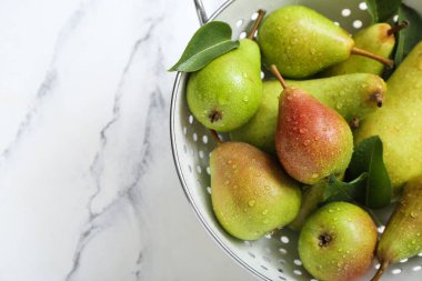 Beyaz mermer masa üzerinde olgun armutlarla Colander, yakın plan.