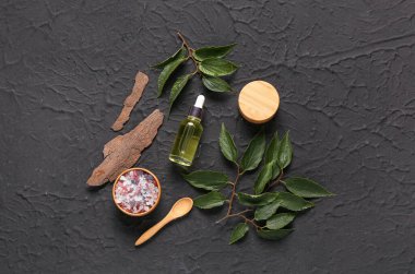 Siyah zemin üzerinde deniz tuzu bulunan şişe ve kozmetik ürünleri.