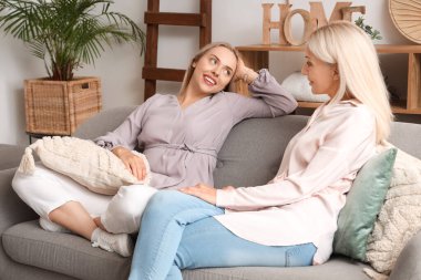 Annesi kanepede oturan ve birlikte vakit geçiren mutlu, genç bir kadın.