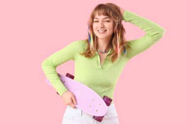 Pembe arka planda kaykayı olan genç bir kadın.