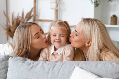 Annesi ve büyükannesiyle evde öpüşen tatlı küçük bir kız.