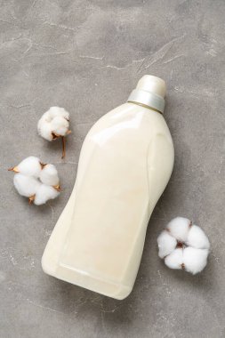 Gri grunge arka planda pamuk çiçekli bir şişe deterjan.