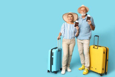 Mavi arka planda pasaportları ve bavulları olan olgun bir çift. Seyahat kavramı
