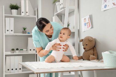 Klinikteki küçük bebeği olan kadın çocuk doktoru.