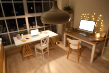 Geceleri masaları ve parlayan ışıkları olan ofisin bulanık görüntüsü