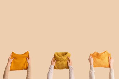 Bej arka planda katlanmış kazaklı kadınlar