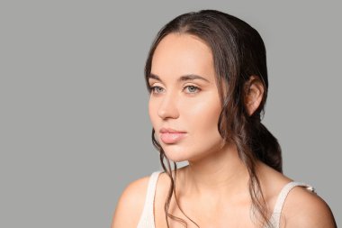 Gri arka planda güzel dudakları olan genç bir kadın, yakın plan.