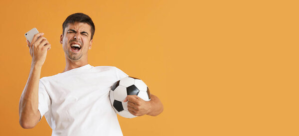 Happy man with soccer ball and mobile phone on yellow background with space for text. Concept of sports bet