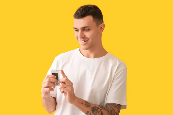 stock image Diabetic young man using glucometer on yellow background