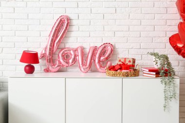 İçinde balonlardan, hediye kutularından ve oturma odasında saksıdan yapılmış sevgi sözcüğü olan bir dolap. Sevgililer Günü kutlaması