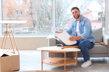 Young man with manual assembling table at home