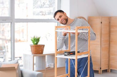 Genç adam raf ünitesini evde monte ediyor.