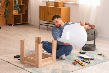 Evdeki ahşap masayı elle monte eden genç adam.