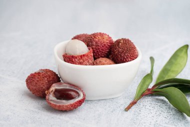 Lezzetli litchi meyveli kase ve arka planda yapraklar, yakın plan.