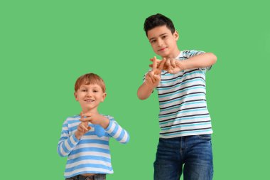 Yeşil arka planda hashtag hareketleri yapan sevimli çocuklar.