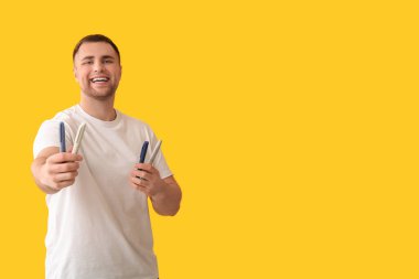 Sarı arka planda tükenmez kalemleri olan yakışıklı, mutlu, şeker hastası bir adam.