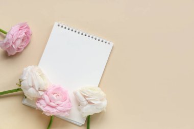 Bej arkaplanda açık not defteri olan güzel ranunculus çiçekleri