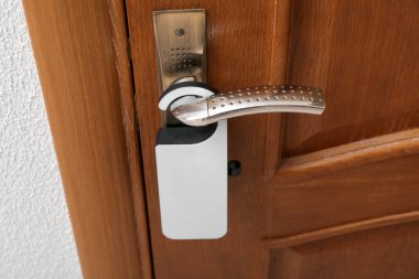 Otel odasında askısı olan koyu ahşap kapı, yakın plan.