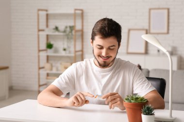 Evde glukometre kullanan şeker hastası genç bir adam.