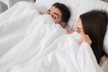 Genç çift yatakta battaniyenin altında yalan