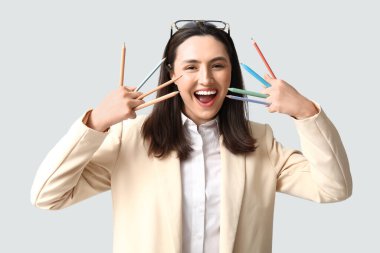 Hafif arka planda kalemleri olan komik iş kadını.