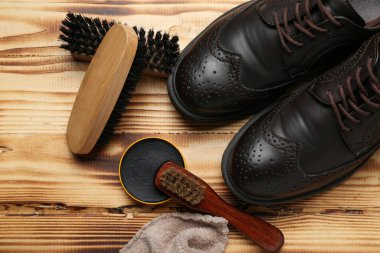 Ahşap arka planda fırçalar, parlak ayakkabılar, kumaş ve ayakkabı cilası.