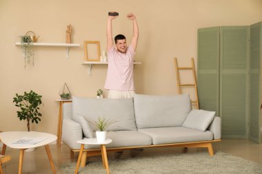 Uzaktan kumandalı genç adam oturma odasında televizyon izliyor.