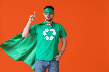 Turuncu arka planda çevreci süper kahraman gibi giyinmiş genç adam şaşırdı. Ekoloji kavramı