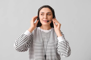 Gri arka planda kulaklık takan kadın teknik destek ajanı