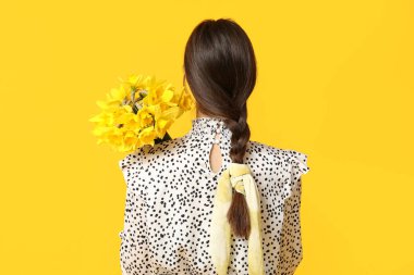 Sarı arka planda güzel narsisli çiçekleri olan güzel bir kadın.