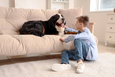 Oturma odasında sevimli tüylü köpeği olan bir çocuk.